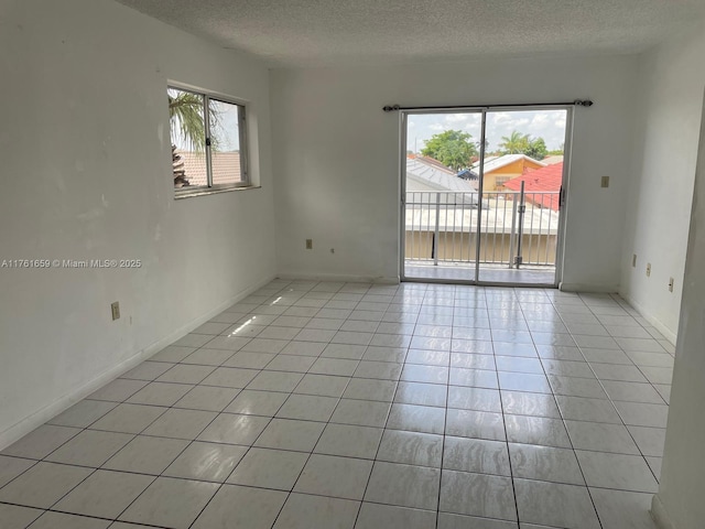 unfurnished room featuring light tile patterned floors, baseboards, and a textured ceiling