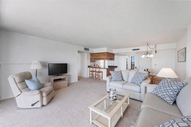 living area featuring visible vents, light colored carpet, and a notable chandelier