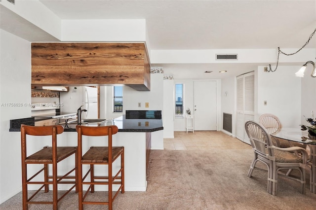 kitchen with dark countertops, visible vents, carpet floors, white appliances, and a sink