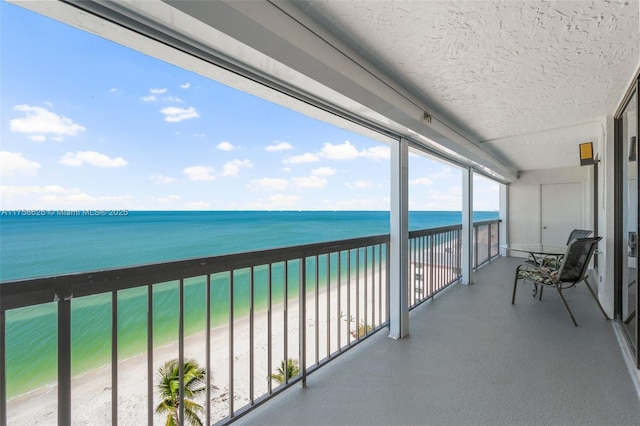 balcony with a water view and a view of the beach