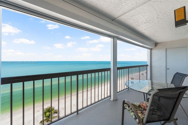 balcony featuring a view of the beach and a water view