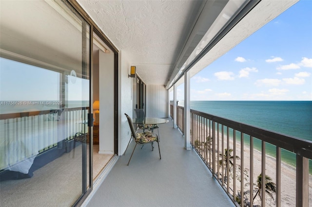 balcony with a beach view, a water view, and a sunroom