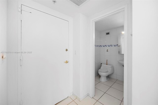 5601 Collins Ave Unit 1604, Miami Beach, FL 33140 - bathroom with tile patterned flooring, visible vents, toilet, and tile walls