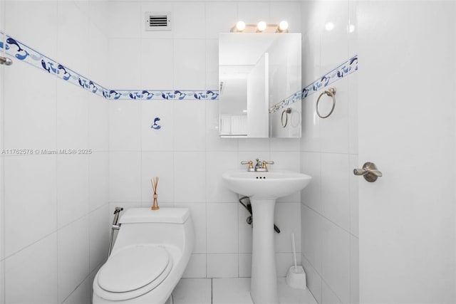 5601 Collins Ave Unit 1604, Miami Beach, FL 33140 - bathroom featuring visible vents, toilet, and tile walls