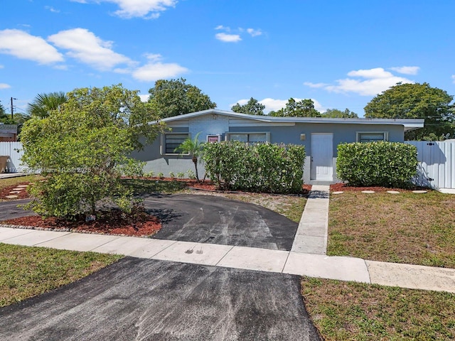 view of front of property with aphalt driveway, stucco siding, a front lawn, and fence