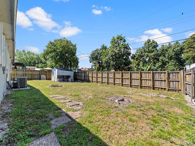 view of yard with a storage unit, cooling unit, an outdoor structure, and a fenced backyard