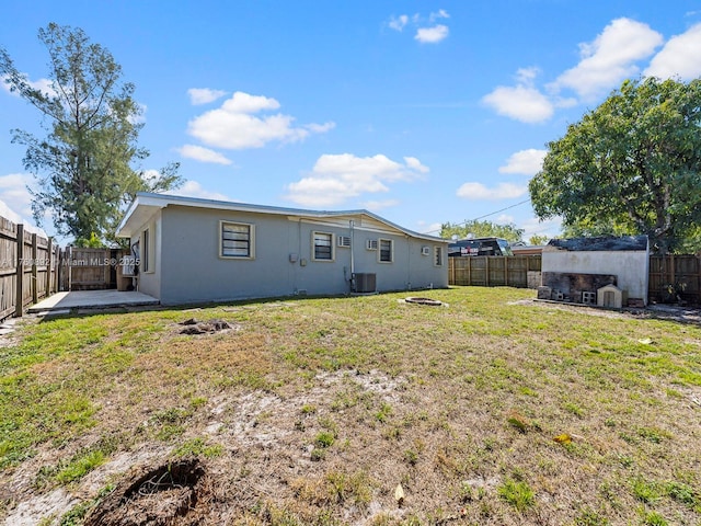 rear view of property featuring central air condition unit, a fenced backyard, and an outdoor fire pit