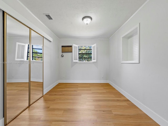 unfurnished bedroom with a closet, multiple windows, a textured ceiling, and light wood-style flooring