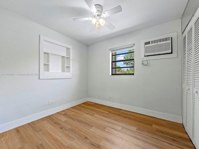 empty room featuring built in features, a ceiling fan, baseboards, an AC wall unit, and light wood-type flooring