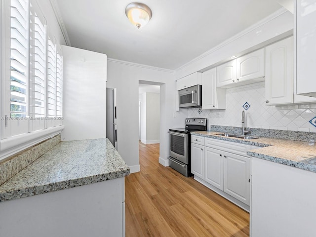 kitchen featuring appliances with stainless steel finishes, crown molding, light wood-style floors, and a sink