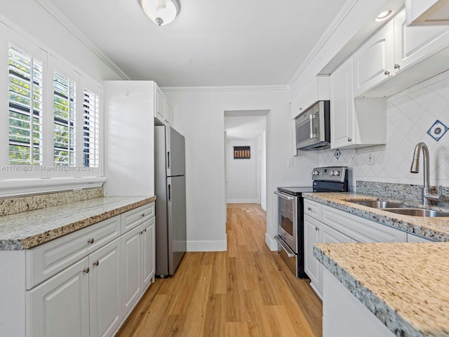 kitchen featuring crown molding, decorative backsplash, appliances with stainless steel finishes, white cabinets, and a sink