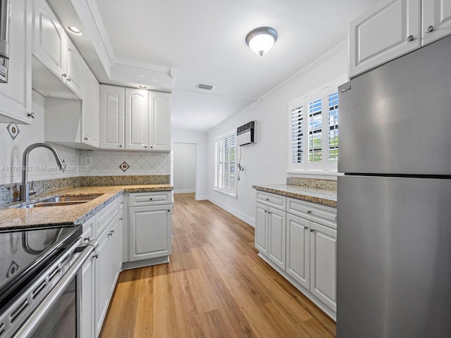 kitchen with crown molding, visible vents, freestanding refrigerator, and a sink