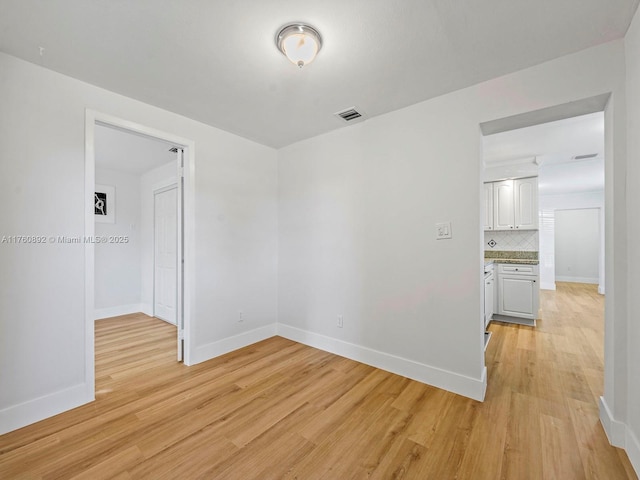 empty room with visible vents, baseboards, and light wood-style flooring