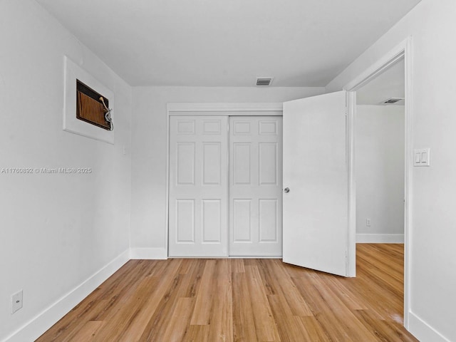 unfurnished bedroom featuring visible vents, light wood-type flooring, a closet, and baseboards