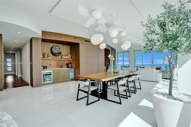 dining room featuring wine cooler, a notable chandelier, and a community bar