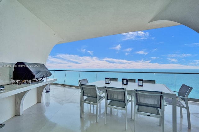 balcony with outdoor dining area and a water view