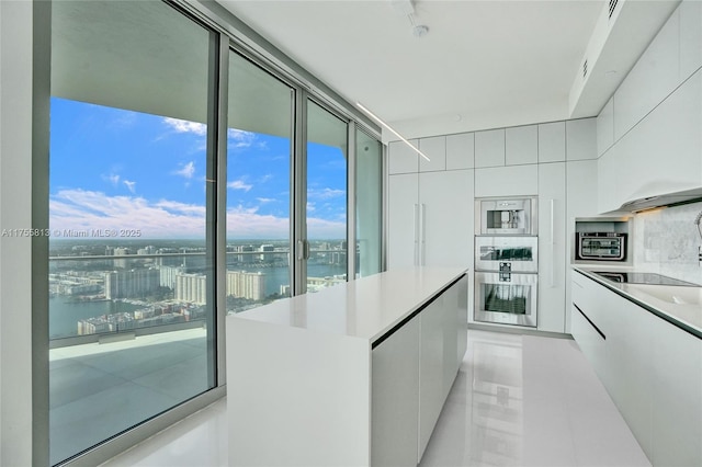 kitchen with stainless steel appliances, light countertops, white cabinets, a water view, and modern cabinets