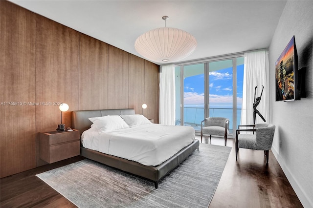 bedroom with dark wood-style floors, access to exterior, baseboards, and expansive windows