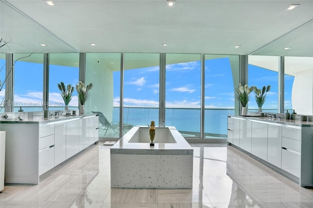 full bath with vanity, a wall of windows, a bath, and a water view