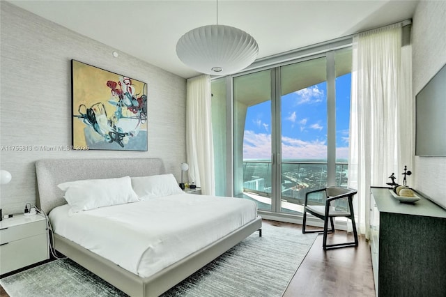 bedroom featuring a wall of windows and wood finished floors