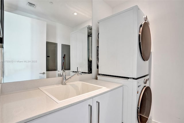 washroom featuring visible vents, stacked washer and clothes dryer, laundry area, and a sink