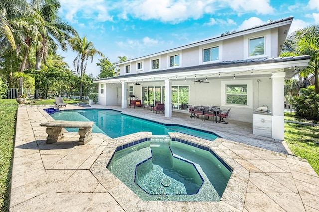 view of swimming pool featuring outdoor dining space, a patio, fence, a pool with connected hot tub, and ceiling fan