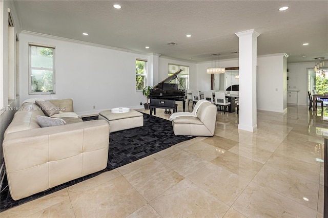 living area with crown molding, a wealth of natural light, ornate columns, and a chandelier