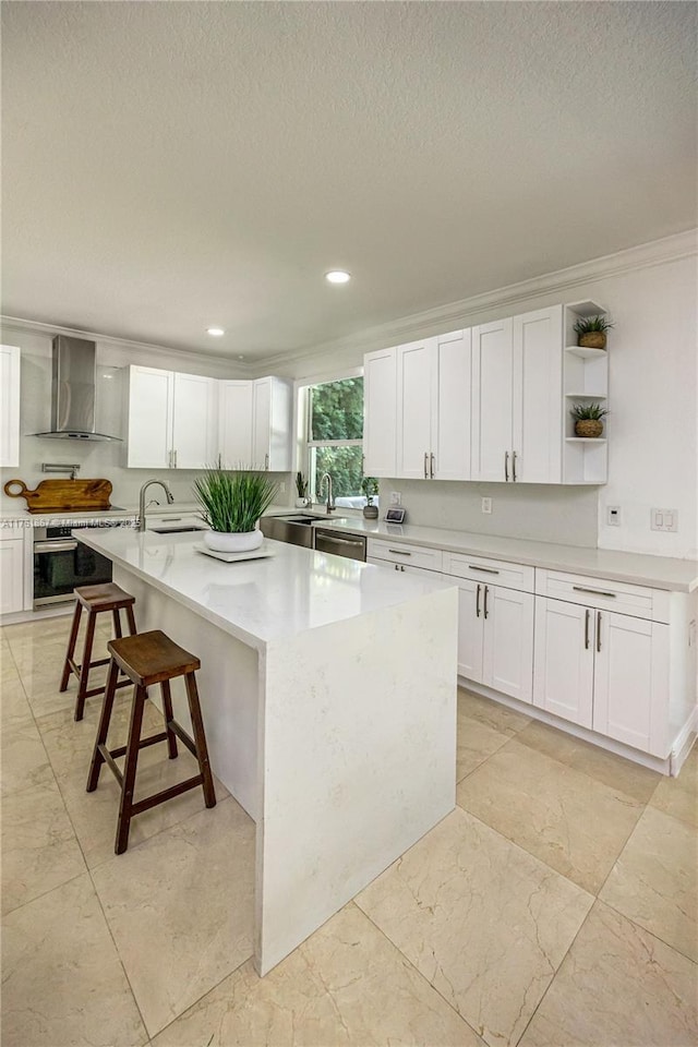 kitchen featuring a center island with sink, open shelves, wall chimney range hood, white cabinets, and light countertops