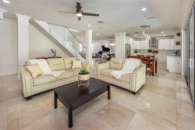 living area featuring visible vents, baseboards, recessed lighting, a textured ceiling, and ornate columns