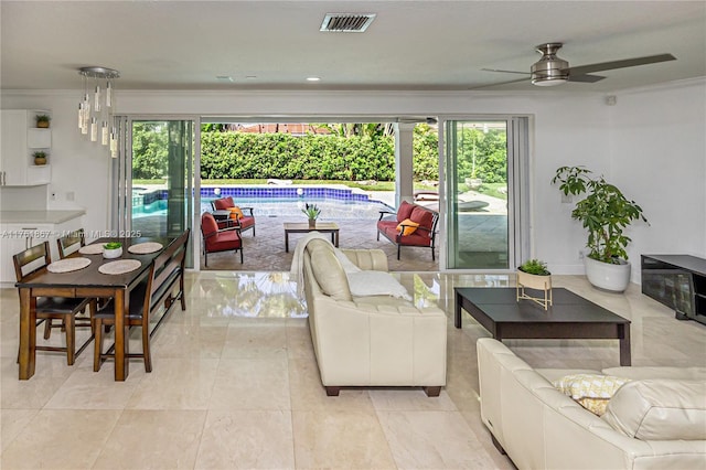 living room featuring visible vents, baseboards, a ceiling fan, and ornamental molding