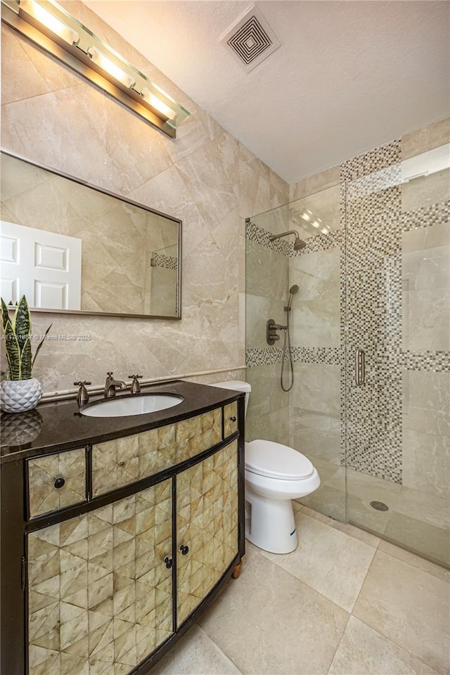 bathroom featuring vanity, visible vents, a stall shower, tile walls, and toilet