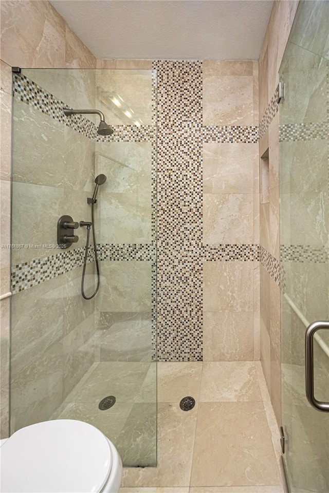 bathroom featuring toilet and a shower stall