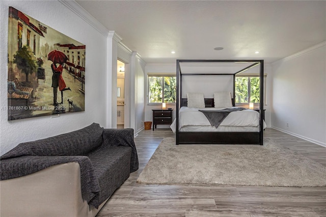 bedroom featuring connected bathroom, crown molding, baseboards, and wood finished floors