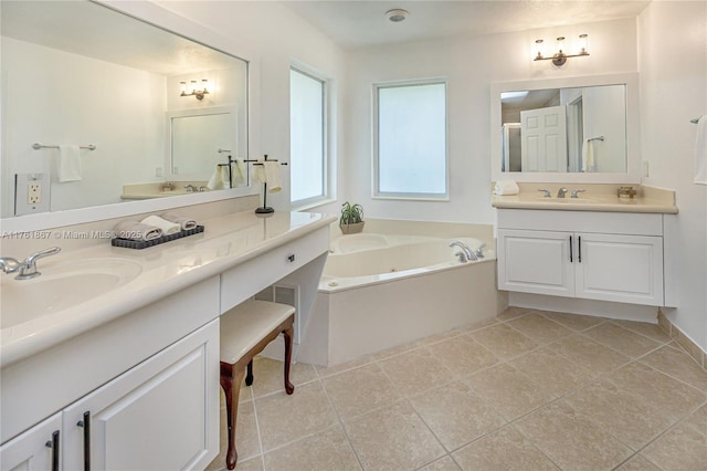 bathroom with tile patterned flooring, a tub with jets, two vanities, and a sink