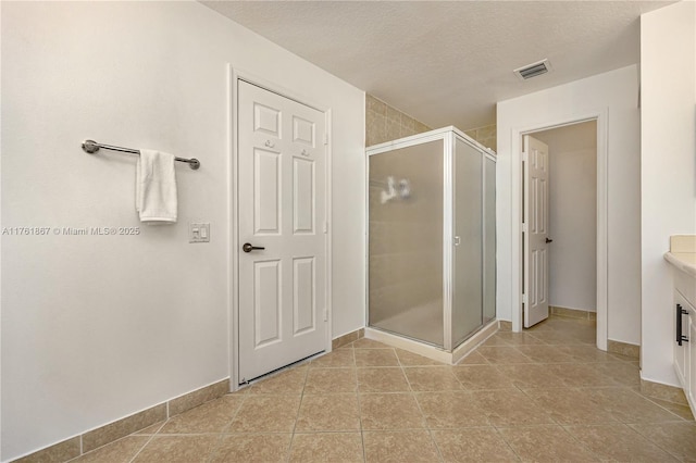 full bathroom with tile patterned flooring, visible vents, vanity, a stall shower, and a textured ceiling