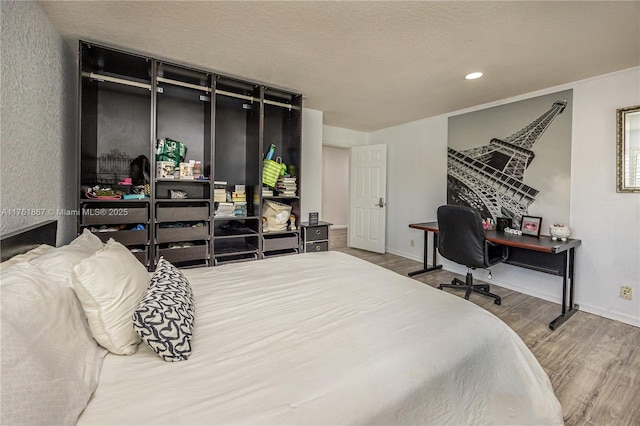 bedroom with recessed lighting, wood finished floors, baseboards, and a textured ceiling