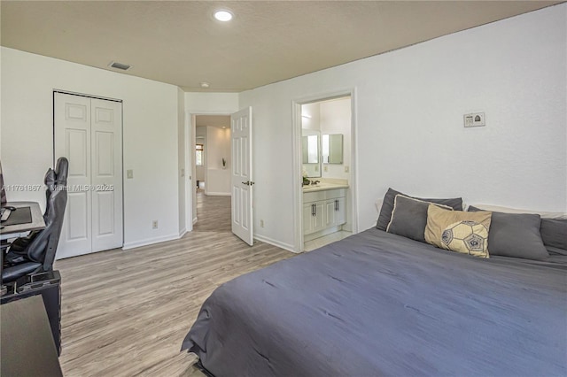 bedroom featuring visible vents, baseboards, a closet, ensuite bathroom, and light wood-type flooring