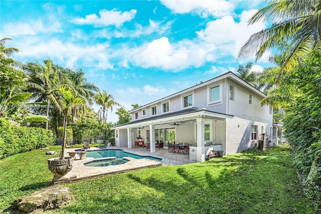 rear view of house featuring stucco siding, a yard, an outdoor pool, an in ground hot tub, and a patio area