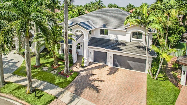 view of front of property featuring stucco siding, decorative driveway, a garage, and a front lawn