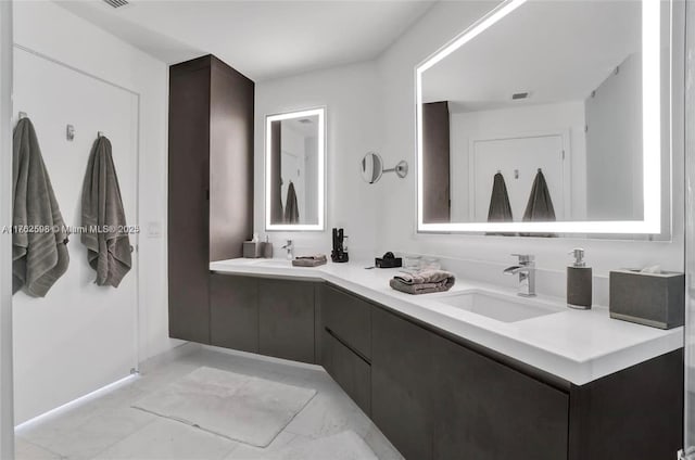 full bath with double vanity, marble finish floor, and a sink