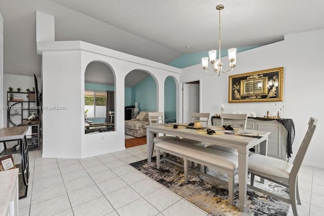 dining room with arched walkways, light tile patterned floors, a notable chandelier, and vaulted ceiling