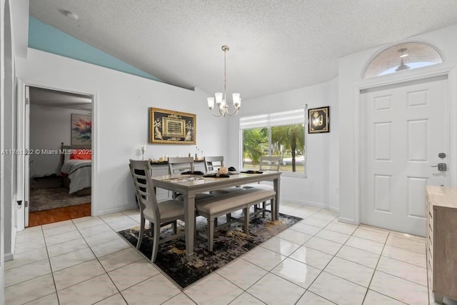 dining space featuring a notable chandelier, a textured ceiling, light tile patterned flooring, and vaulted ceiling