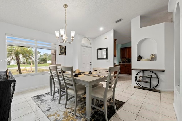 dining room featuring visible vents, a chandelier, vaulted ceiling, light tile patterned floors, and a textured ceiling