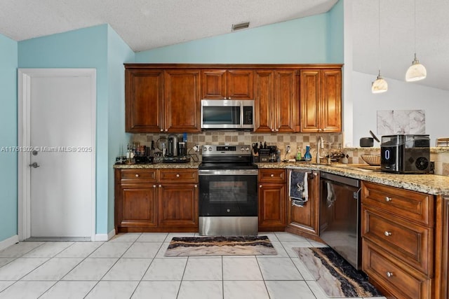 kitchen featuring light stone counters, visible vents, appliances with stainless steel finishes, and lofted ceiling