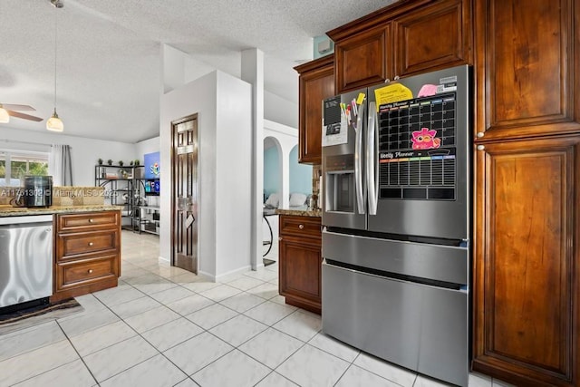 kitchen featuring light stone counters, light tile patterned flooring, arched walkways, appliances with stainless steel finishes, and a textured ceiling