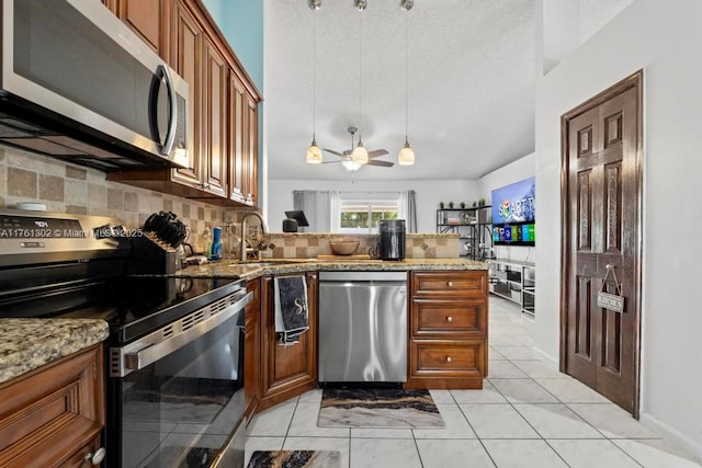 kitchen featuring brown cabinets, a sink, light stone counters, stainless steel appliances, and decorative backsplash