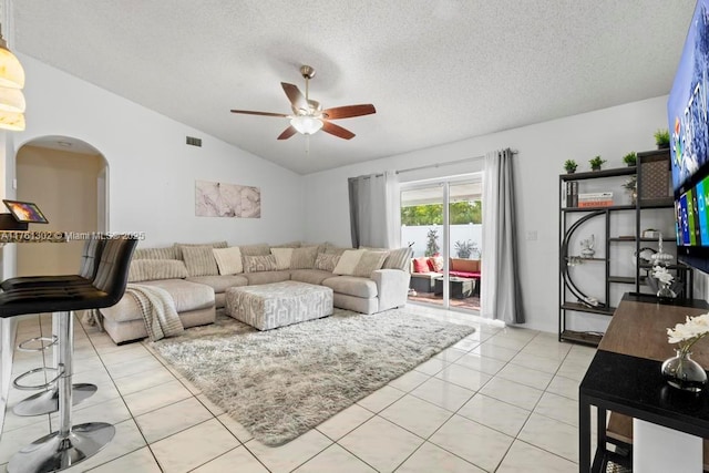 living area with visible vents, lofted ceiling, arched walkways, light tile patterned flooring, and a textured ceiling