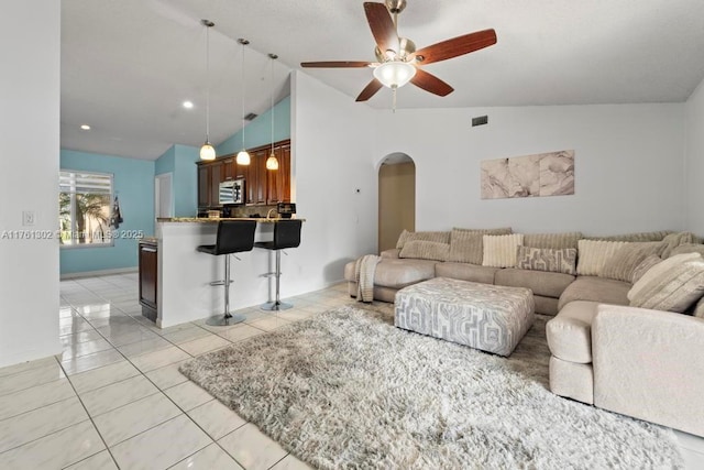 living room featuring visible vents, a ceiling fan, arched walkways, light tile patterned flooring, and lofted ceiling