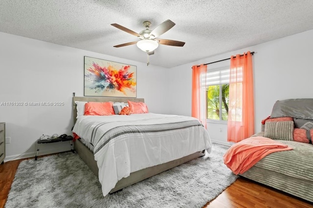 bedroom featuring baseboards, a textured ceiling, ceiling fan, and wood finished floors