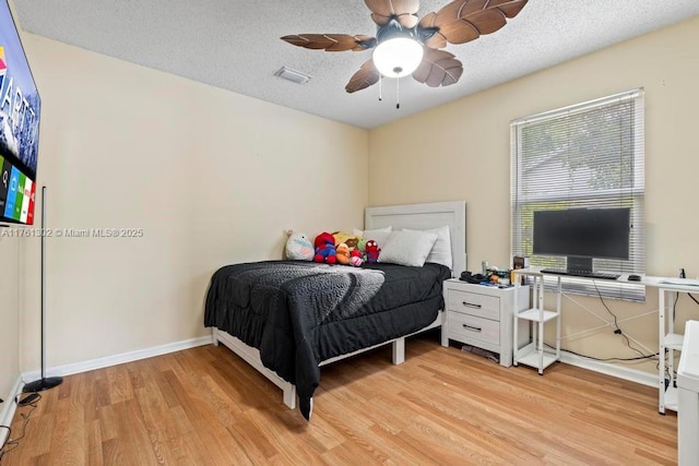 bedroom with visible vents, a ceiling fan, a textured ceiling, wood finished floors, and baseboards